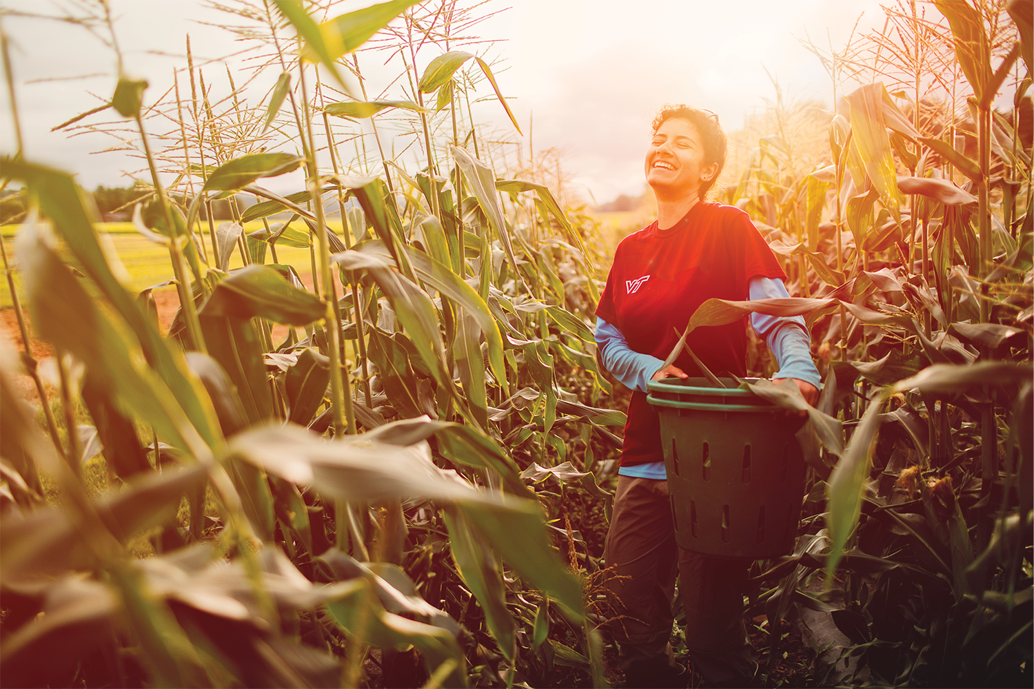 Image of a girl smiling in a cornfield holding a planter
